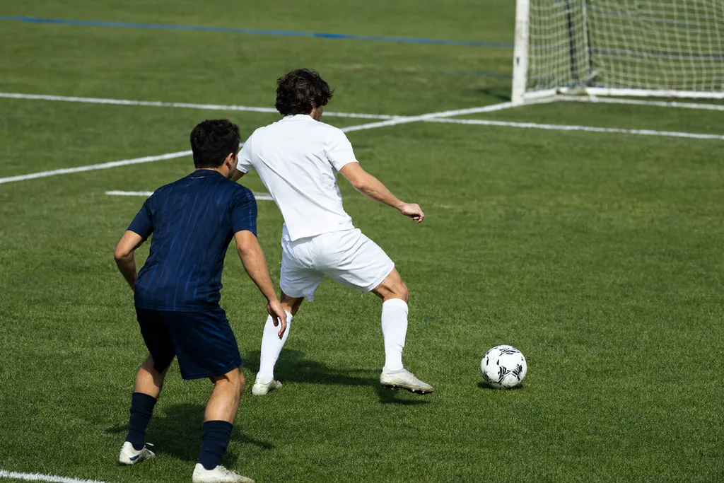 Forward seen from behind on the shoulder of a defender inside the penalty area